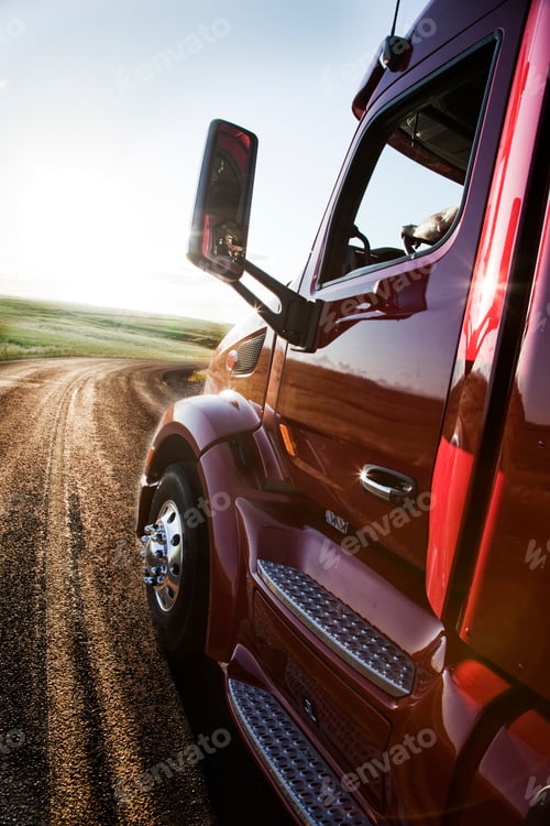 Preview: Close up side view looking forward of a commercial truck on a highway at sunset.