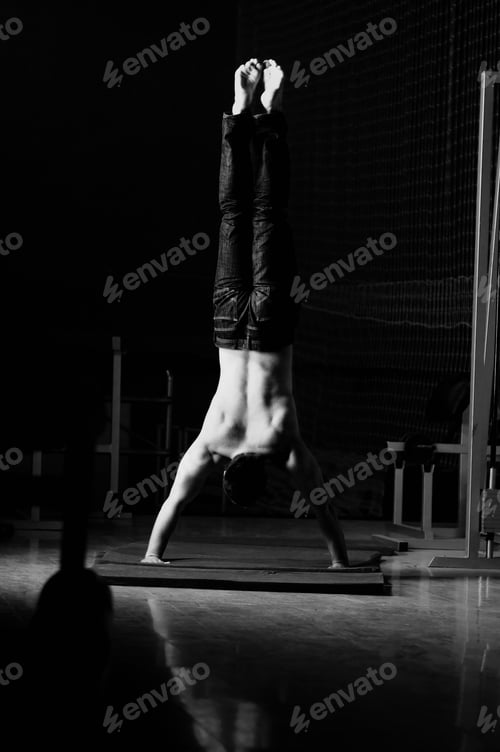 Preview: young man performing handstand in fitness studio