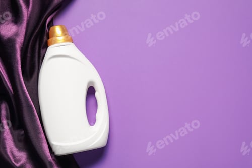 Preview: Bottle of fabric softener and color cloth on purple background, top view. Space for text