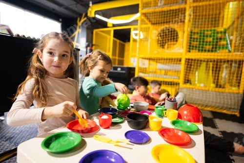 Preview: Two sisrers playing in kids kitchen at children play center.
