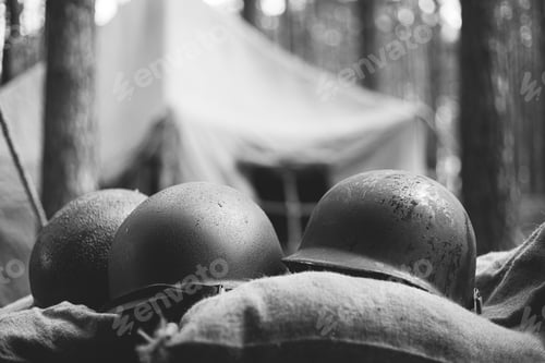 Preview: Metal Helmets Of United States Army Infantry Soldier At World War II. Helmets Near Camping Tent In