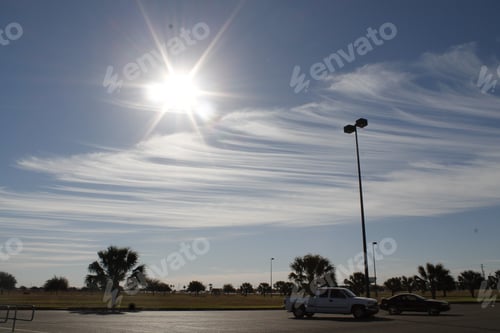 Preview: Cars parked in a park parking lot with the Sun shining bright in the sky