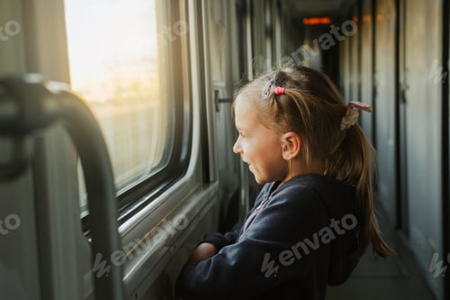 Preview: Child in train looking though train window on sunset
