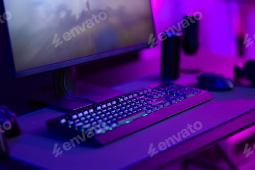Preview: Modern gaming setup with keyboard, mouse, and monitor in a dimly-lit room with purple lighting
