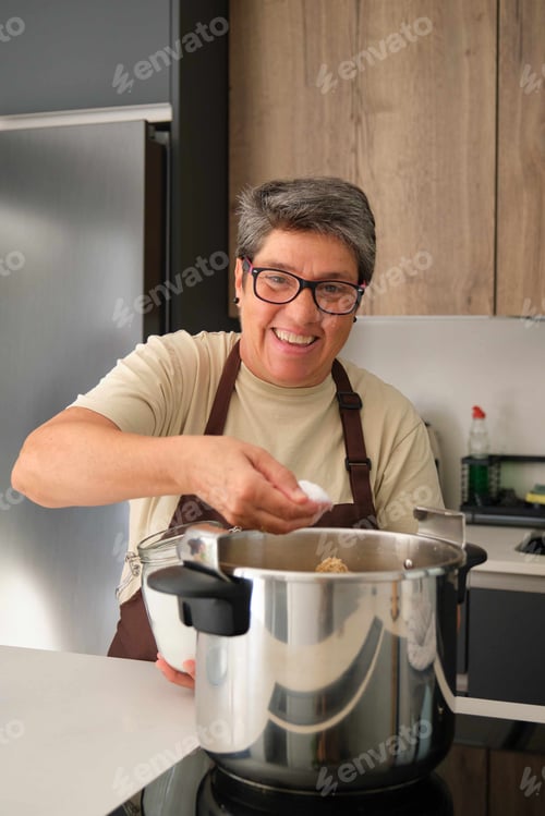 Preview: Mature Spanish woman adding salt to the stew in a pressure cooker.