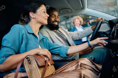 Preview: Happy multiracial couple testing their new car in a showroom.