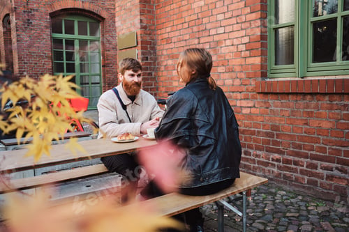 Preview: Young man happily looking at girlfriend on date in street cafe