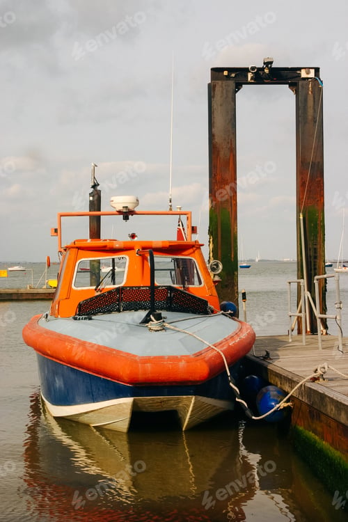 Preview: Orange and blue ship next to the wooden pier