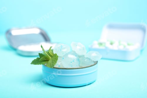 Preview: Open box with tasty mint candies and leaves on color background