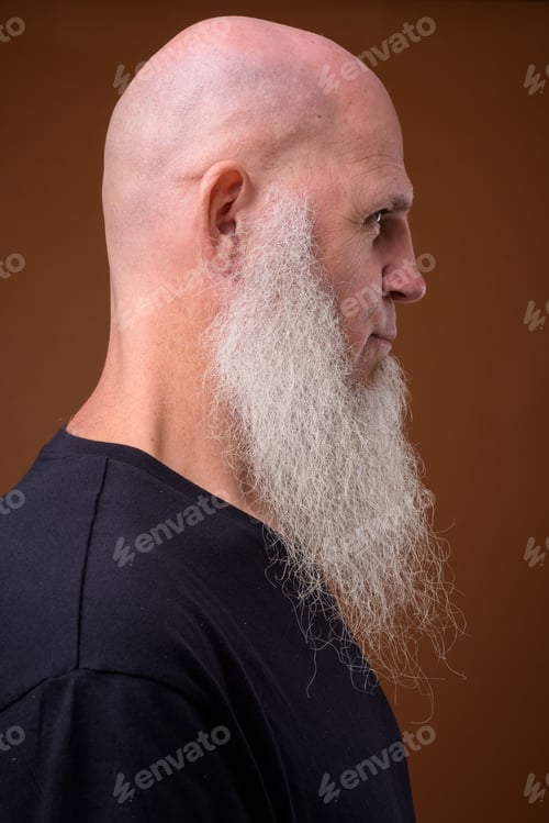 Preview: Mature bald man with long gray beard against brown background