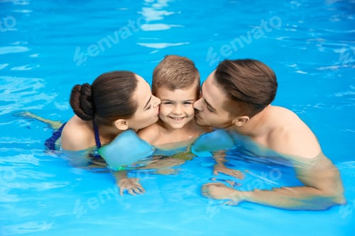 Preview: Young family with little son in swimming pool on sunny day