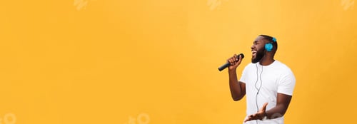 Preview: Portrait of cheerful positive chic handsome african man holding microphone and having headphones on
