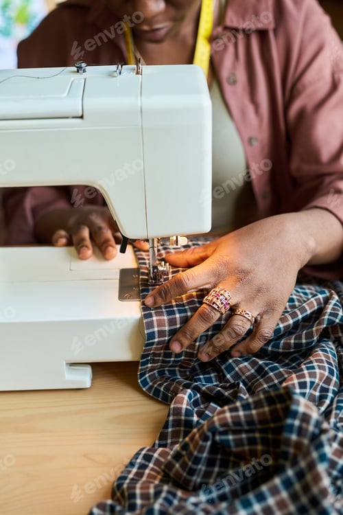 Preview: Middle Aged Black Woman Sewing Plaid Fabric with Sewing Machine in Thrift Shop