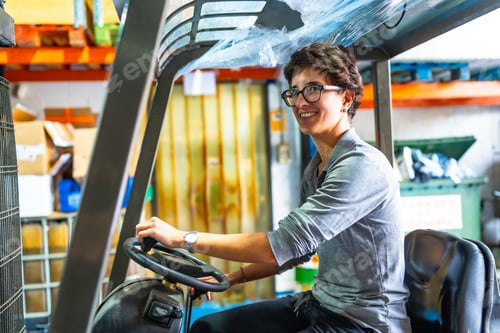 Preview: Happy woman driving forklift in a metallurgic factory