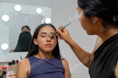 Preview: Makeup artist applying powder to young latina woman