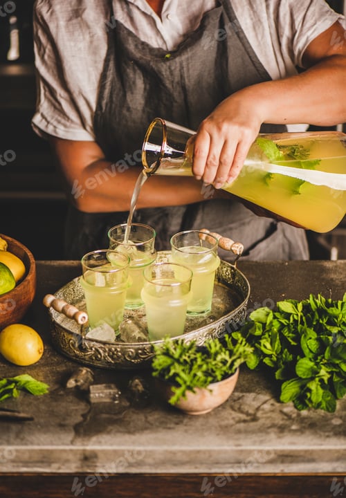 Visualização: Mãos de mulher fazendo limonada caseira fresca no balcão da cozinha