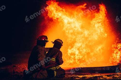 Preview: Fearless Firefighters Battling Blaze with Water and Extinguishers.