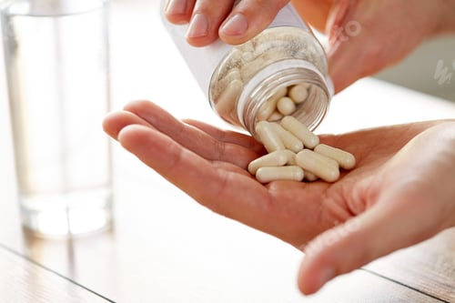 Preview: close up of man pouring pills from jar to hand