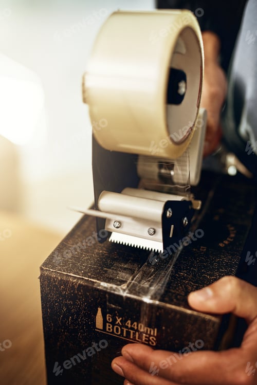 Preview: All sealed and ready to ship. Closeup shot of a delivery man sealing a box with tape.