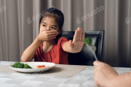 Preview: Little cute kid girl refusing to eat healthy vegetables. Children do not like to eat vegetables.