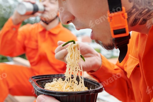 Construction Workers Enjoying Lunch Outdoors in Orange Uniforms