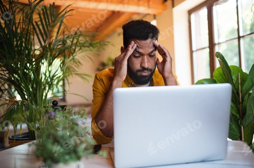 Preview: Frustrated young man with laptop working indoors, home office concept
