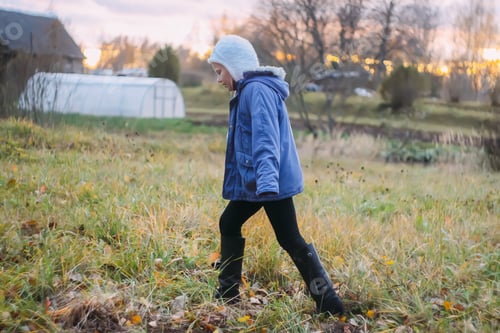 Preview: Little girl walks on rural field in autumn day.