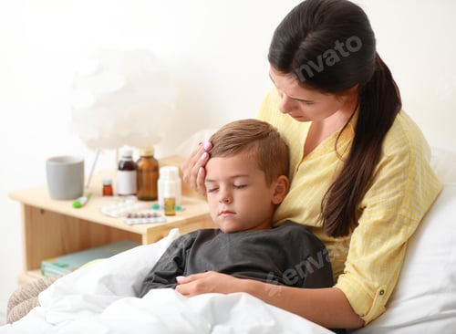 Preview: Mother taking care of her little son suffering from cold in bed