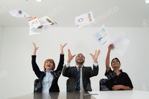 Preview: Three joyful business professionals tossing papers in the air.
