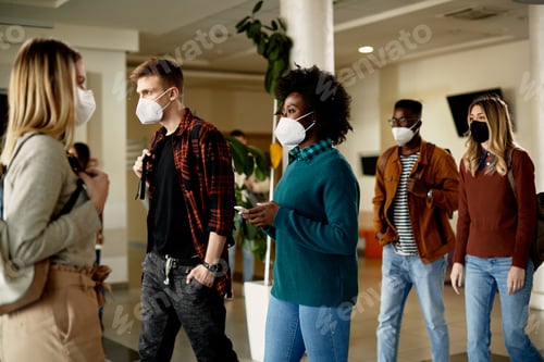 Preview: Group of students wearing face masks while walking through university hallway.