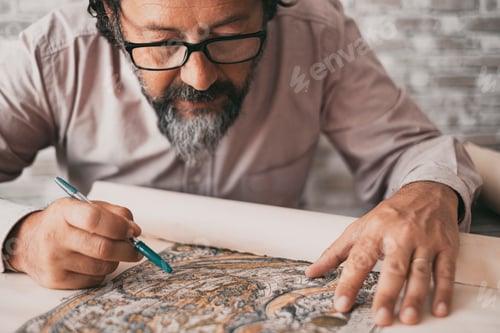Preview: Close up portrait of man busy studying a paper design map on the desk table. Professional