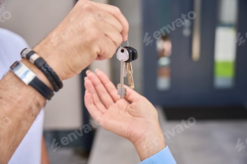 Preview: Close-up of man's hand, giving woman hand keys from house
