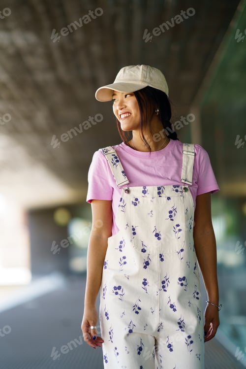 Preview: Positive young Chinese woman walking through university, smiling with happiness
