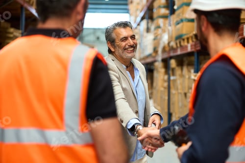 Preview: Manager and warehouse worker shaking hands on a deal