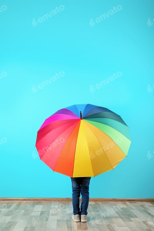 Preview: Little boy with rainbow umbrella near color wall. Space for text
