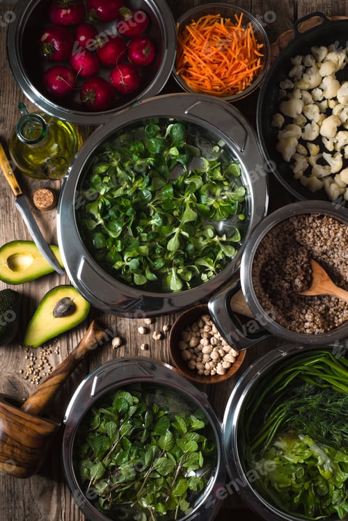 Preview: Vegetables, chickpeas, herbs in bowls in the water, half an avocado on the table