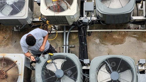 Preview: Young man HVAC technician millennial in unique job testing A/C units for efficiency at beach condo.