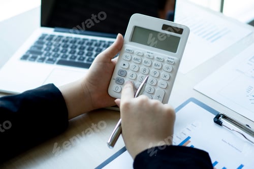 Preview: Female finance workers are using a calculator to calculate the company's earnings from a bar graph.