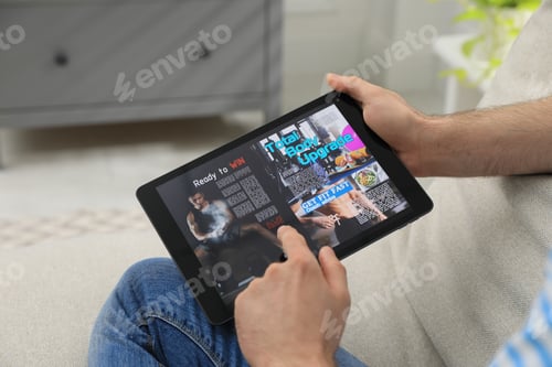 Preview: Man reading online magazine on tablet indoors, closeup