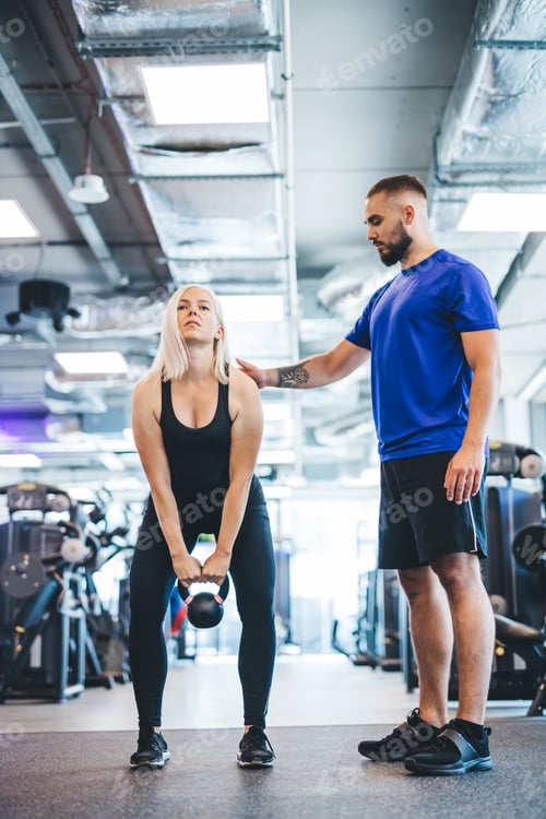 Preview: Woman working out with personal trainer at a gym.
