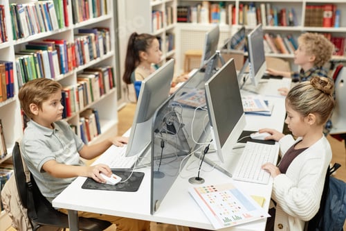 Preview: Children Sitting at Table with Computers in Lit Programming Class