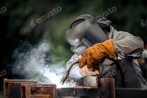 Preview: Man in a protective mask welding metal construction