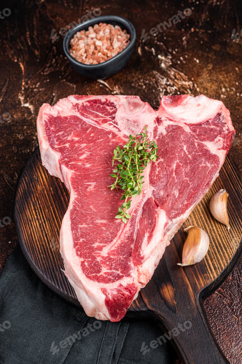 Preview: Raw Porterhouse steak, marbled beef meat on a wooden board. Dark background. Top view