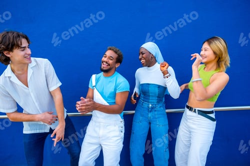 Preview: Multi-ethnic friends having fun dancing next to a blue wall