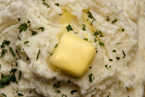 Preview: Closeup shot of creamy mashed potatoes topped with melted butter and fresh parsley