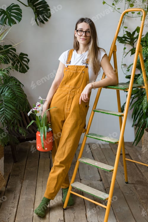 Preview: Woman gardener holding orchid in old red milk can at home garden, love of houseplants, hobby.