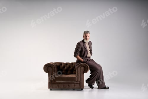 Preview: Full length shot of fashionable mature man with beard wearing elegant suit looking at camera