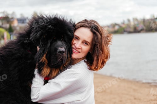Preview: Smiling woman hugging tibetian mastiff dog looking at camera outdoors. Girl and dog playing together