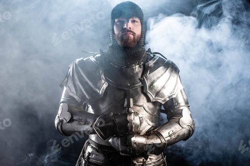 Preview: handsome knight in armor looking at camera and holding sword on black background