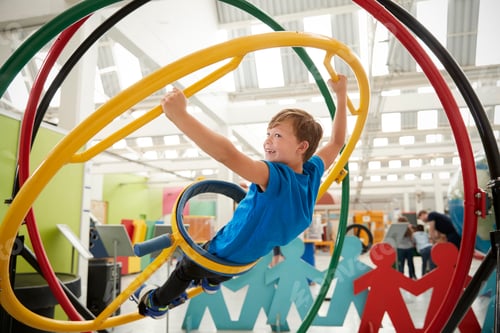 Preview: Schoolboy in science centre using human gyroscope, side view